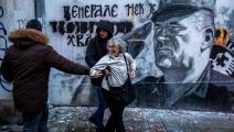 رجُلا أمن بملابس مدنية يعتقلون ناشطةً قذفت جدارية مُجرم الحرب ملاديتش في بلغراد بالبيض، 9 تشرين الثاني/ نوفمبر 2021 (Getty)