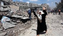 فلسطينية خلفها الدمار في غزة (أشرف عمرة/الأناضول)