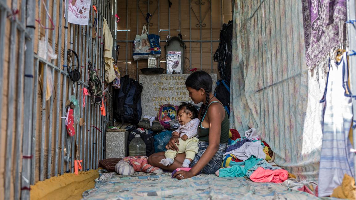 TOPSHOT-VENEZUELA-CRISIS-HOMELESS-CEMETERY TOPSHOT - A young woman and a baby rest at a makeshift refuge at the southern general cemetery in Caracas, on February 16, 2021. - Desecrated tombs have become the home of many homeless in Venezuela. (Photo by Pedro Rances Mattey / AFP) (Photo by PEDRO RANCES MATTEY/AFP via Getty Images)