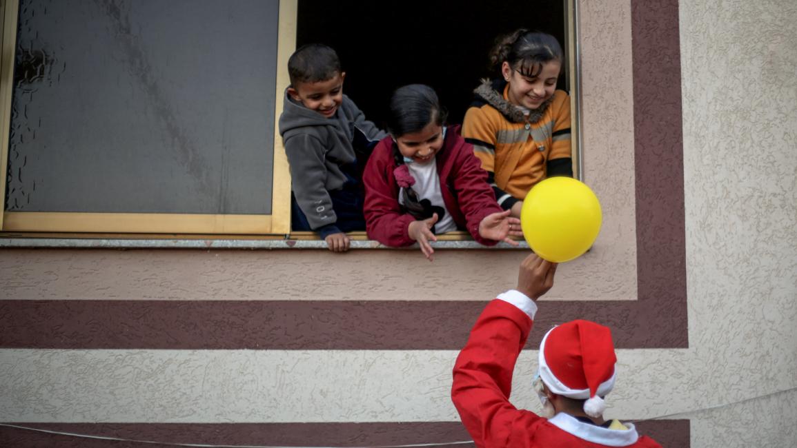 يوزع بالونات على أطفال في غزة (يوسف مسعود/ Getty)