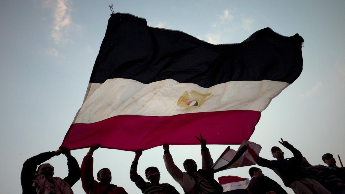 متظاهرون يلوحون بعلم مصري في ميدان التحرير في القاهرة بعد الإعلان عن تنحي مبارك في 11/2/ 2011 (Getty)