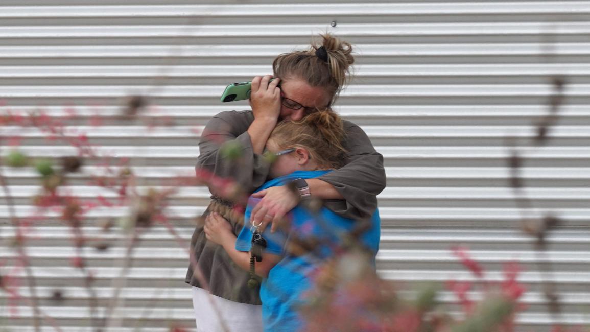امرأة تبكي وتضم طفلة صغيرة بعد حادثة إطلاق النار في مدرسة في بمدينة أوفالدي/ تكساس/ فرانس برس