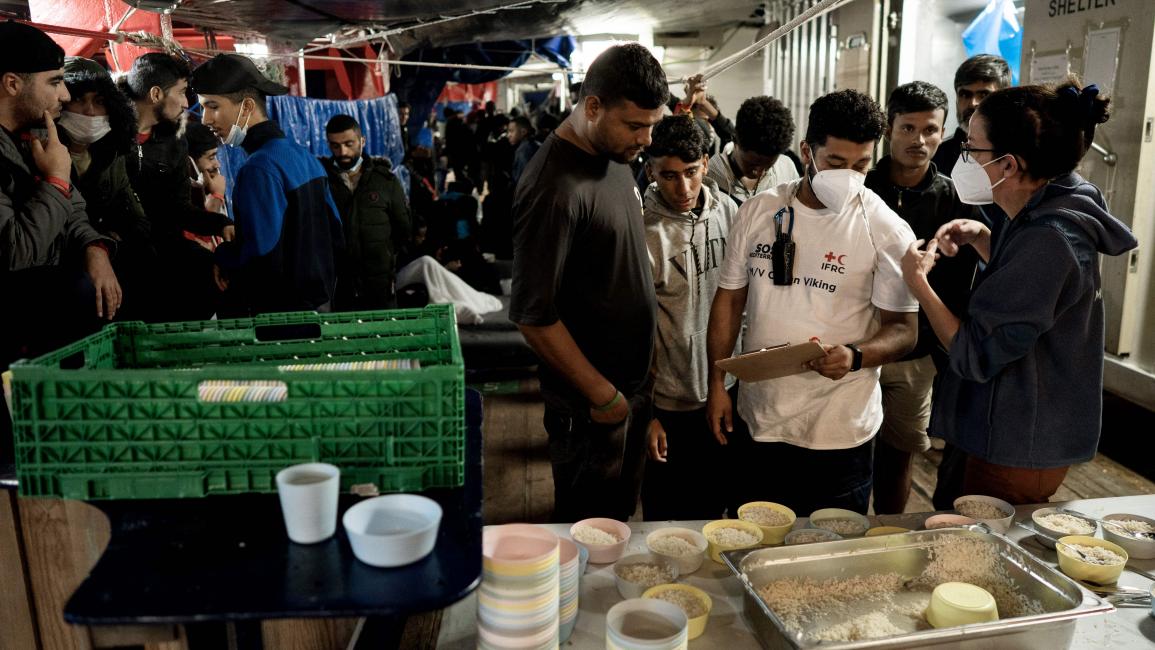 مهاجرون ناجون يحصلون على وجبات غذائية (فينسينزو سيركوستا/ فرانس برس)