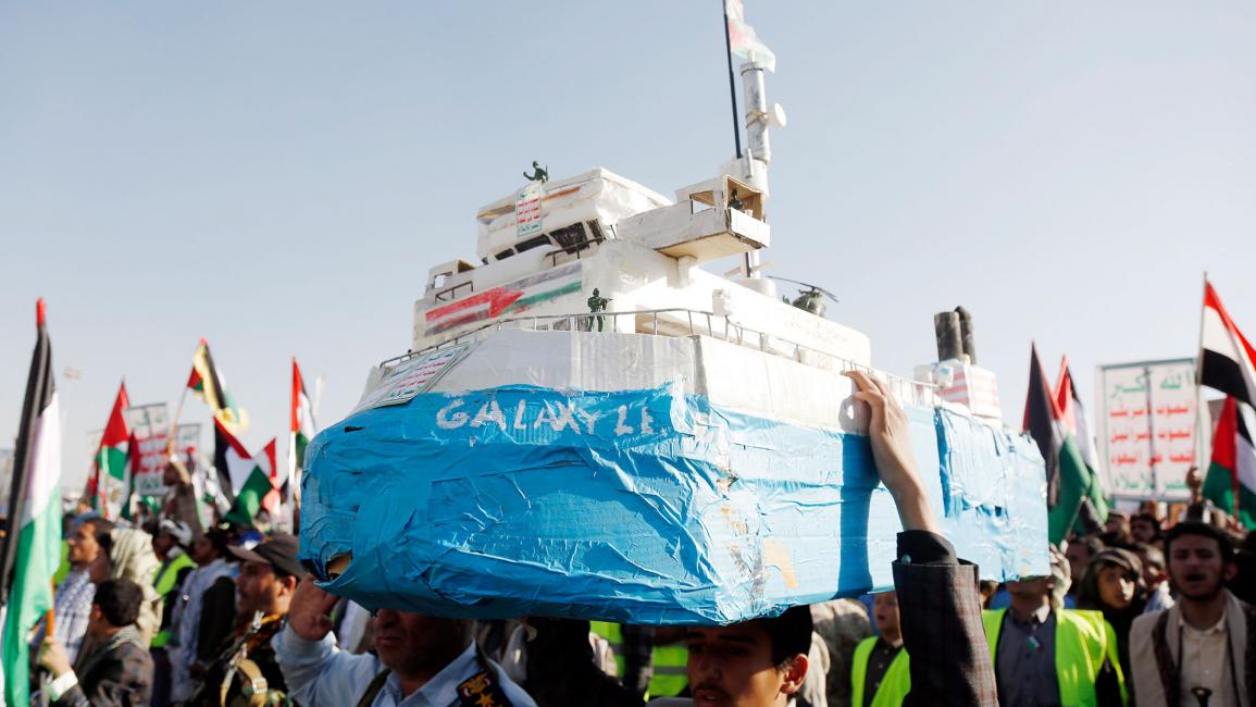 رجل يمني يحمل نموذجاً لسفينة الشحن الإسرائيلية غالاكسي ليدر (محمد حمود/Getty)