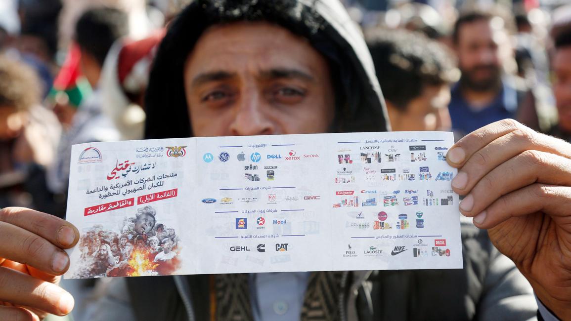 متظاهر يمني يعرض ملصقاً لمقاطعة البضائع الأميركية والإسرائيلية (محمد حمود/Getty)