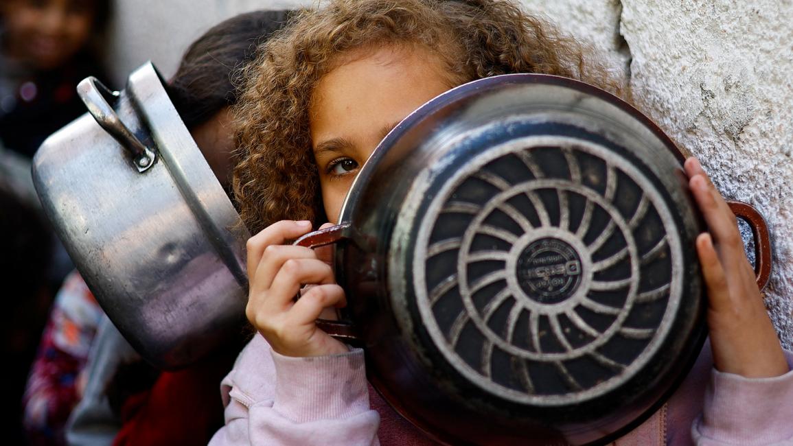 طفلة تخفي وجهها خلف إناء فارغ (رويترز/إبراهيم أبو مصطفى)