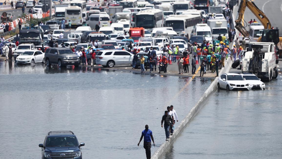 أشخاص يسيرون على طول طريق سريع غمرته المياه (فرانسوا نيل/Getty)