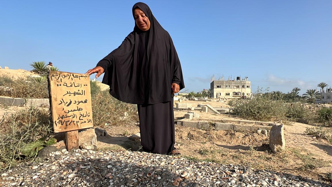 سيدة فلسطينية تقف بجانب قبر أحد شهداء غزة (أنس زياد فتيحة/الأناضول)