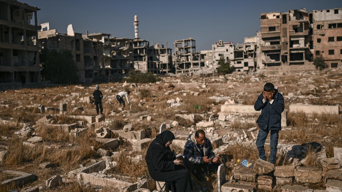 فلسطينيون يقرأون الفاتحة عند قبر أحد أقاربهم في مقبرة في مخيم اليرموك بعد سقوط الأسد (14/12/2024فرانس برس)