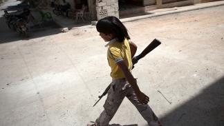 صبي سوري يمشي حاملاً بندقية بمعرة النعمان، 13 يونيو 2013 (فرانس برس)