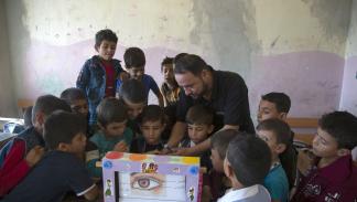 معلم سوري يشارك تلاميذه صنع الوسائل التعليمية (قاسم رماح/الأناضول)