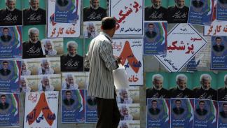 إيراني يمر أمام ملصقات انتخابية في طهران أمس (فاطمة بهرامي/الأناضول)