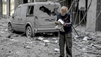 رجُل فلسطيني يتصفّح كتاباً بين الأنقاض في مدينة غزّة