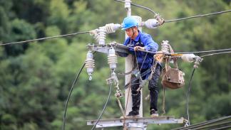 يصلحون شبكة كهرباء قرية سيان في رونغان الصينية، 2 يوليو 2024 (Getty)