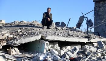 رجل يجلس على أنقاض منزل دُمّر جراء غارة في إدلب، 26 ديسمبر 2023 (عز الدين قاسم/الأناضول)