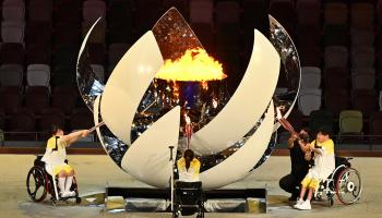 ثلاثة أشخاص معوقين يضيئون الشعلة الأولمبية في استاد طوكيو (شارلي تريبالو/ فرانس برس)