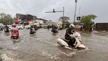 راكبو دراجات نارية وسط فيضانات الهند (إندرانيل موخيرجي/ فرانس برس)