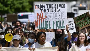 طالب أميركي يرفع لافتة "من النهر إلى البحر فلسطين ستكون حرة" (سيلال جونز/الأناضول)