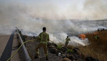 عمال إطفاء إسرائيليون يحاولون إخماد النيران في حقل بهضبة الجولان المحتلة بعد سقوط صواريخ لحزب الله، 2 يونيو 2024 (فرانس برس)