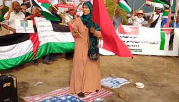 امرأة تدوس العلمين الأميركي والإسرائيلي في وقفة أمام السفارة الأميركية في تونس، 16 يونيو 2024 (العربي الجديد)