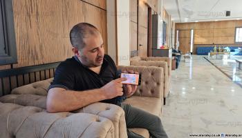 عبد الله النبهان يعرض بطاقته كلاجئ سوري شرعي (العربي الجديد)
