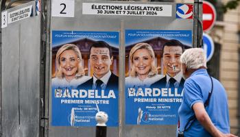 رجل يسير بجوار ملصقات انتخابية ممزقة لمارين لوبان، 30 يونيو 2024 (Getty)