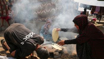 نازحون في خانيونس جنوبي قطاع غزة يحاولون إعداد الخبز، 26 يوليو 2024 (Getty)