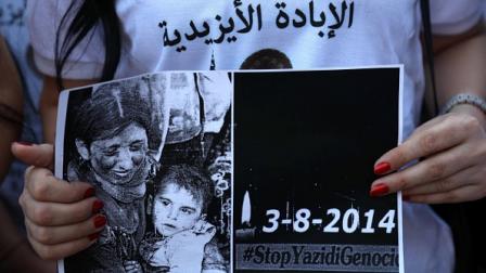 فتاة أيزيدية تحمل صورة لضحايا داعش، دهوك 2 أغسطس 2019 (صافين حميد/فرانس برس)