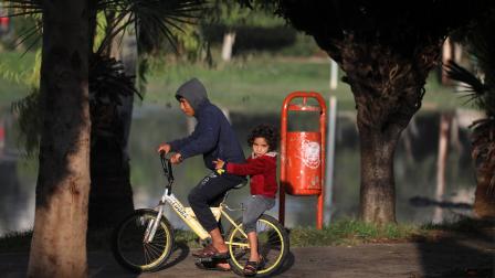 طفلان فلسطينيان على درّاجة في حديقة عامّة بمدينة غزّة، كانون الأوّل/ ديسمبر 2022 (Getty)