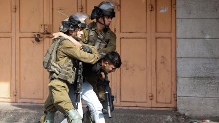جنديان إسرائيليان يعتقلان طفلاً في الضفة الغربية (حازم بدر/ فرانس برس)