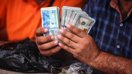 رجل يحسب الدولار بعد صرف شواقل بغزة،2 يوليو 2024،(مجدي فتحي/Getty)