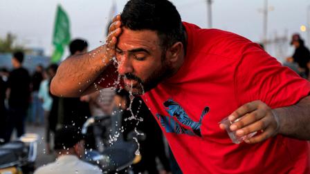 عراقي يغمر نفسه بالماء ليبرد في الناصرية، يونيو 2024 (فرانس برس)